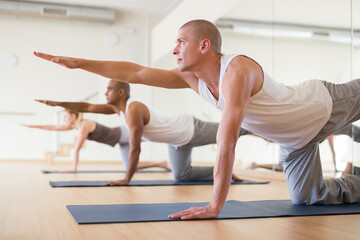 Fototapeta na wymiar Sporty people practicing stretching yoga training in modern class
