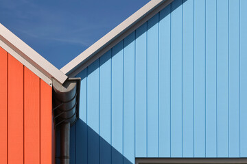 Fototapeta na wymiar Detail photo of painted wood of some Scandinavian like coloured buildings in Lauwersoog, The Netherlands. Orange and blue abstract geometric image with diagonals.