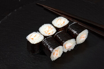 Traditional delicious freshsushi rolls with shrimp on a black background. Sushi roll with rice, cream cheese, avocado, salmon, sesame. Sushi menu. Japanese kitchen, restaurant