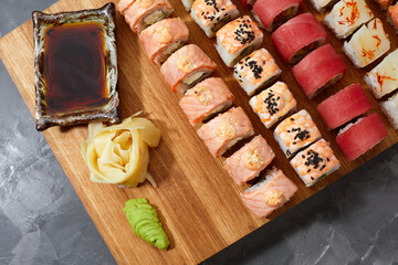 Assortment of different kinds of sushi rolls placed on black stone board. Sushi set with salmon, cucumbers, cream cheese, avocado and sesame seeds. Sushi image for menu