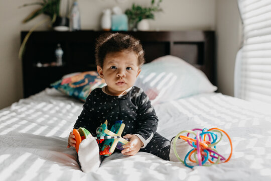 A 7 month old baby playing on the bed