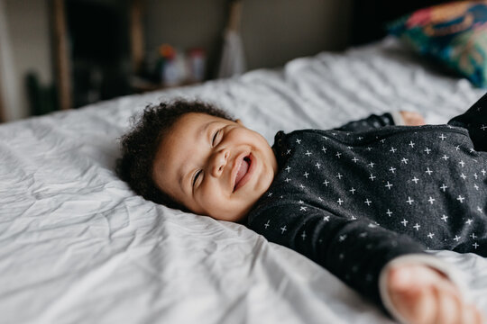 A 7 month old baby playing on the bed