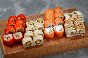 Top view background with set of colorful different kinds of sushi rolls placed on wooden board