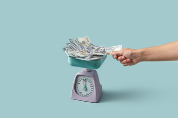 Dollars weighed on scale taken by female hand.