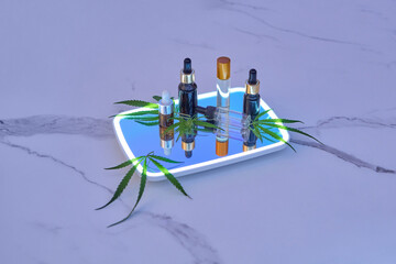 CBD oil bottles with natural cannabis on mirror.
