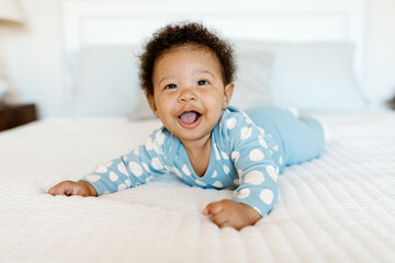 A 7 month old baby playing on the bed