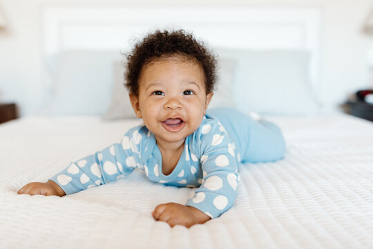 A 7 month old baby playing on the bed