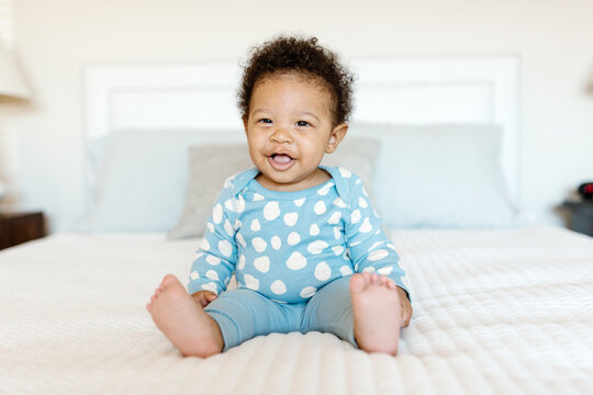 A 7 month old baby playing on the bed