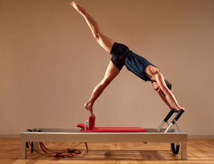 Fit man doing a lunge stretch yoga pilates exercise to strengthen and tone his muscles using a...