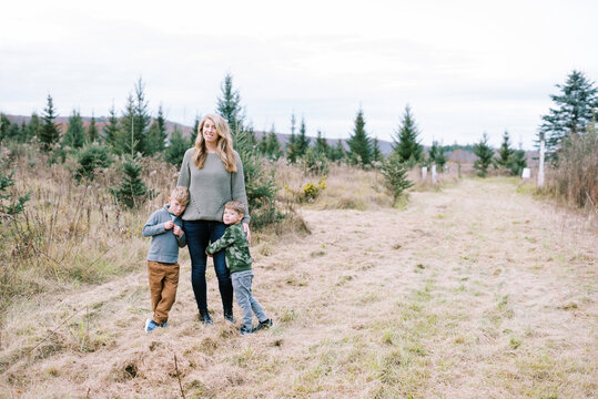 Mother standing with her sons in a field of Christmas trees in winter
