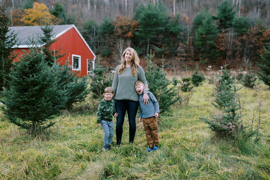 Mother standing with her sons in a field of Christmas trees in winter
