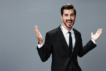Man businessman smiling happily with his teeth raised hands up in a business suit with tie on a dark gray background