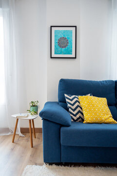 White living room with blue sofa and turquoise poster