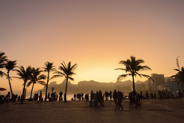 sunset on the beach with palms and people silhouette