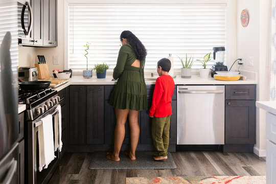 Mother with boy washing plates in kitchen