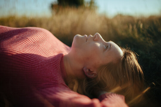 Dreamy Woman Lying in Grass and Looking At Sky 