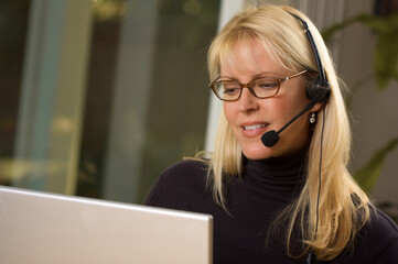 Attractive Businesswoman Wearing Phone Headset Using a Computer