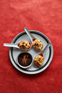 A Plate of Three Dumplings Served in Asian Soup Spoons with Sauce