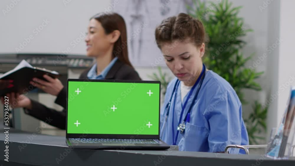 Poster nurse and receptionist working with greenscreen on laptop at facility reception counter. using blank
