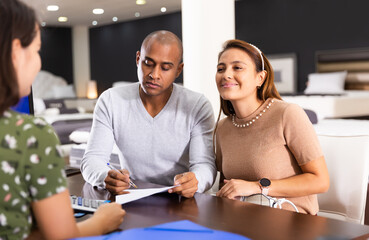 Married couple communicates with mattress shop assistant in a furniture store