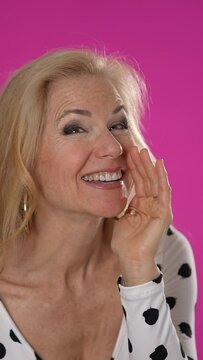 Vertical video portrait of fun woman say hush be quiet with finger on lips shhh gesture posing isolated on pink background in studio. People sincere emotions, lifestyle concept.