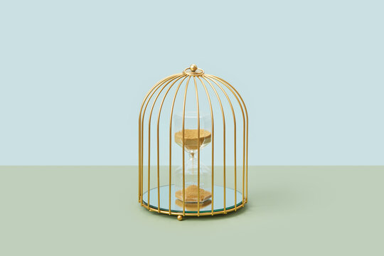 Hourglass with golden sand inside birdcage.