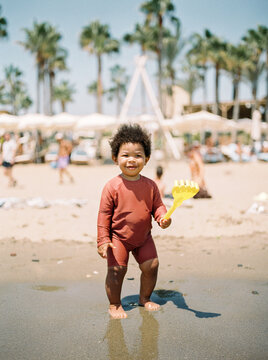  A toddler boy playing at the beach in sand