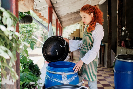 Woman checking the inside of a plastic barrel