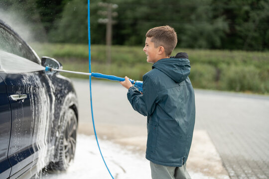 Kid is washing vehicle at manual car wash station