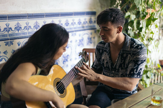 Young Man Teaching His Friend To Play The Guitar