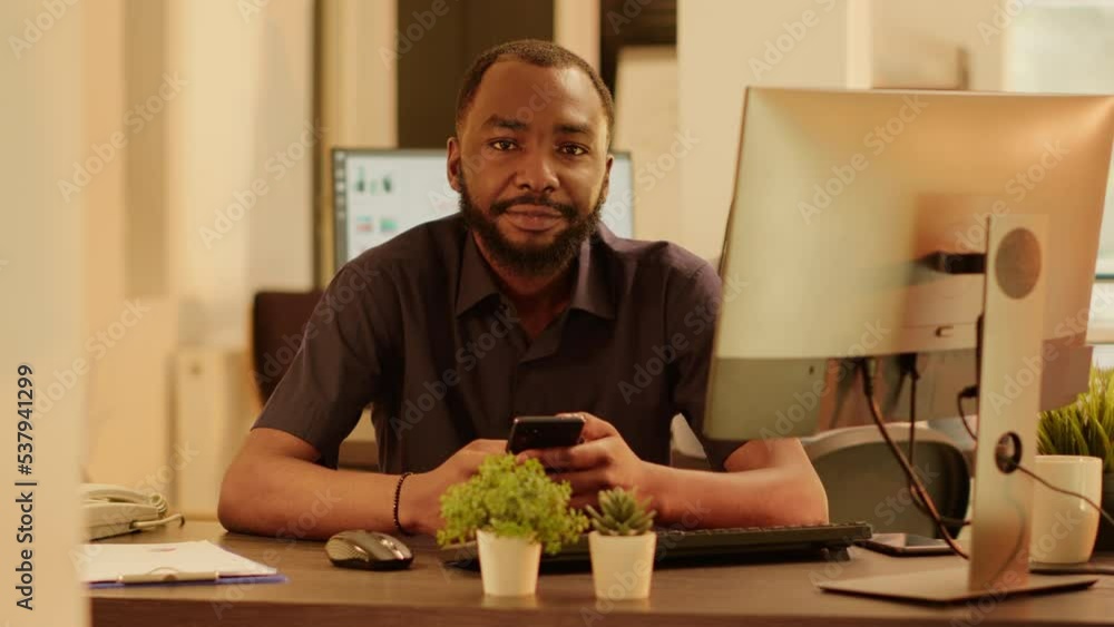 Poster portrait of african american man using smartphone app on computer, planning business presentation an