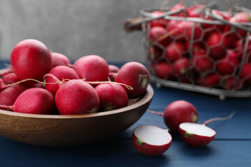 Bowl with fresh ripe radishes on blue wooden table, closeup