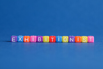 Word EXHIBITIONIST made with colorful cubes on blue background