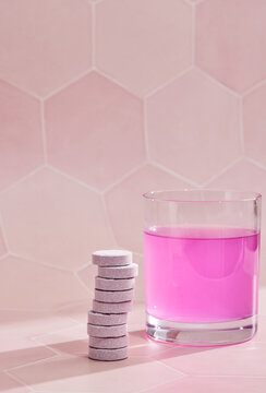 Bright pink carbonated drink and stack of pills