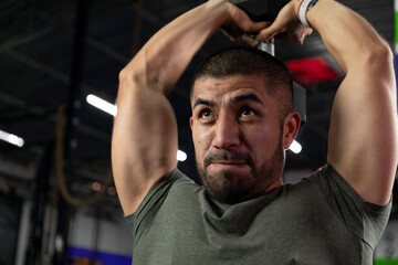 close up of a latino athlete doing triceps exercise in a gym with a dumbbell