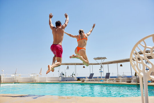 Young Couple Jumping Into Pool