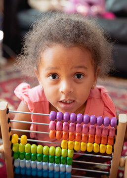 Closeup of a child playing with a rainbow coloured abacus