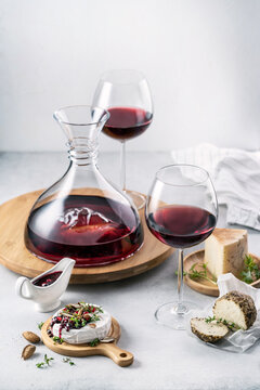Red wine served in a decanter and glasses and a variety of cheeses