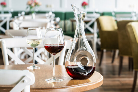 Glasses with red, white wine and a wine decanter in a bright interior