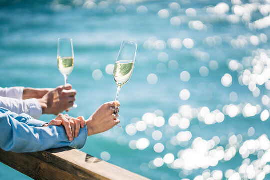 Close up of a couple with champagne in flute goblets with sea on the b