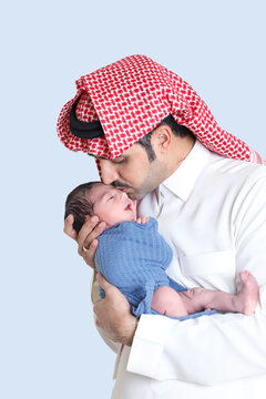 saudi muslim man in traditional dressing holding newborn baby in arms,infant boy wrapped in towel