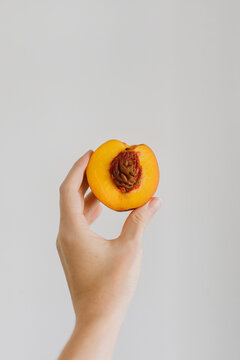A half of a nectarine in a woman hand on light background