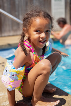 Child Getting Up From Sitting At The Edge Of A Swimming Pool