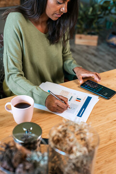 Hispanic woman calculating expenses at home