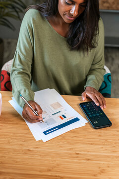 Hispanic woman calculating expenses at home