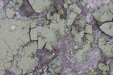 Peeling paint on the wall. Old concrete wall with cracked flaking paint. Weathered rough painted surface with patterns of cracks and peeling. High resolution texture for background and design. Closeup