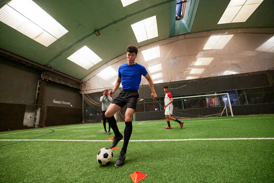 Teenager practicing to on football pitch with friends