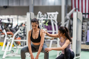 Fototapeta na wymiar Female fitness instructor showing exercise progress to a young athletic woman at the gym and smiling cheerfully while exercising with his fitness coach and training.