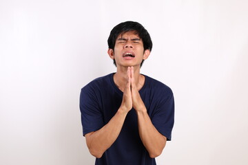 Portrait of young asian man standing with begging or asking gesture. Isolated on white background