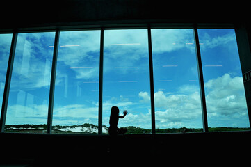 menina com mão na janela observando aeroporto 